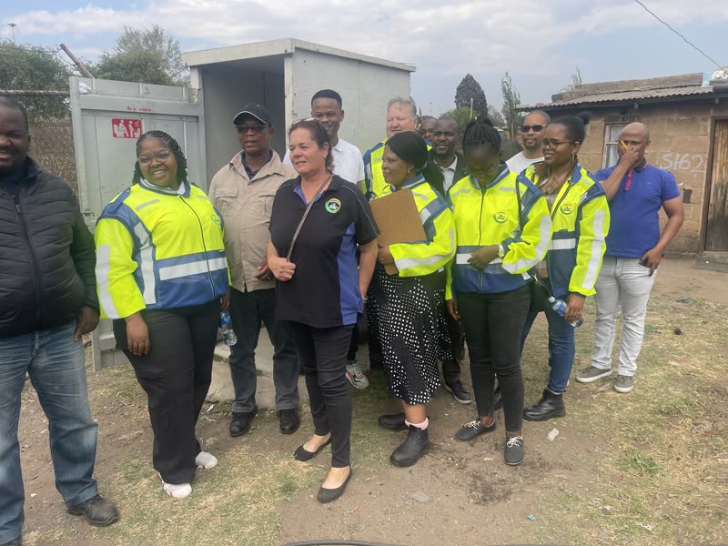 Provincial and municipal officials in high-visibility jackets gathered beside an installed Bio-Separator toilet unit
